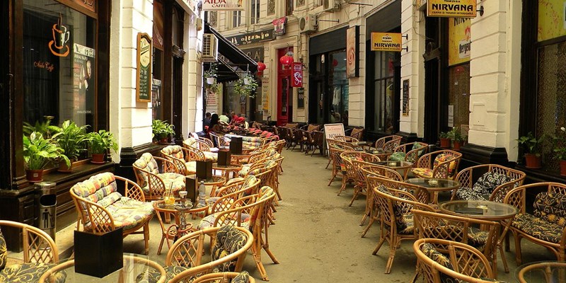 Tourist travel couple with backpacks strolling and walking on Victory street ( Calea Victoriei ). Pedestrian area in the old town of Bucharest