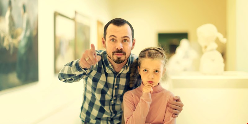 Father and daughter regarding paintings in halls of museum